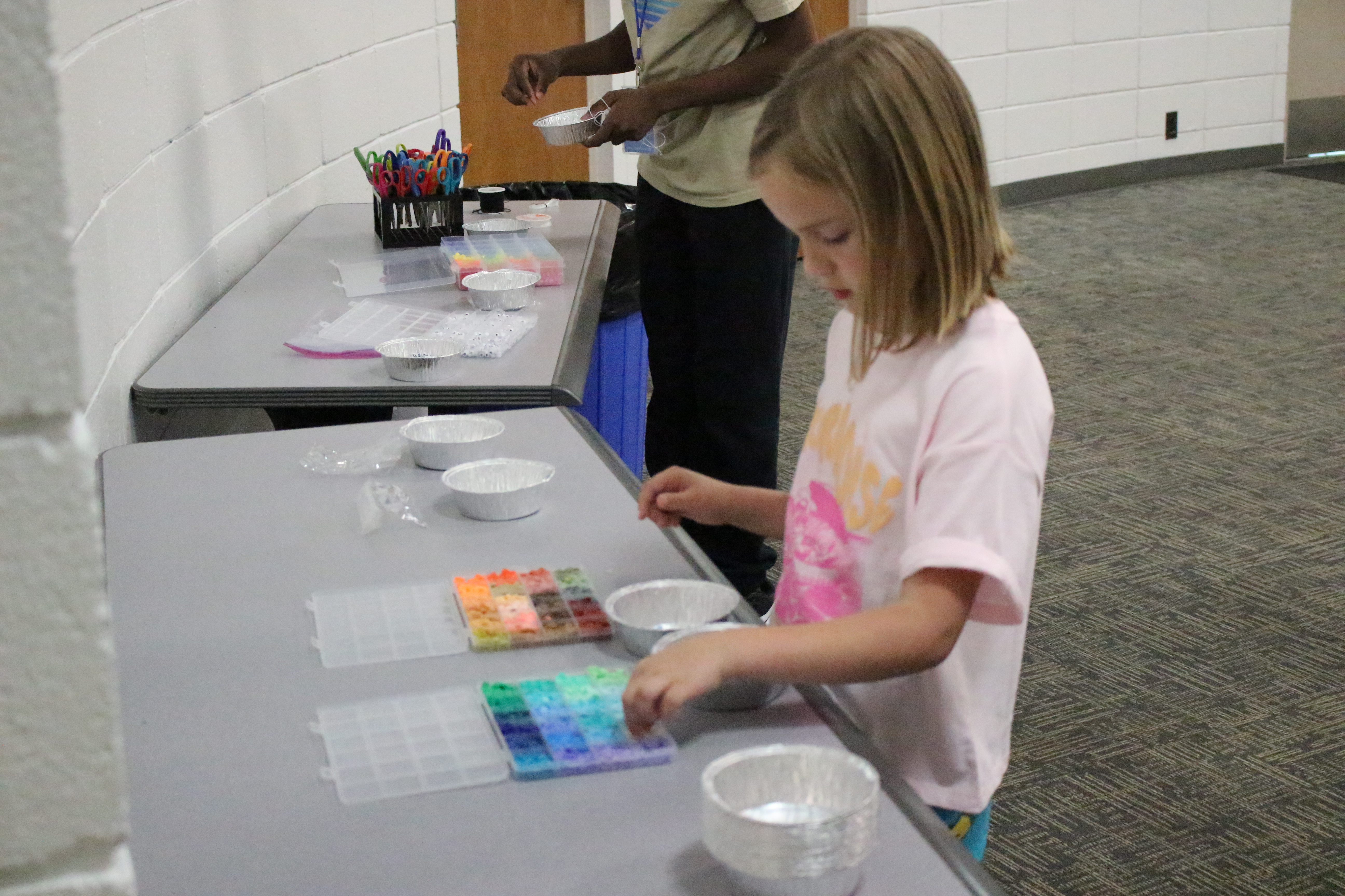 A tween at a CCJPL tween event crafts with paint at a table in the Round Room
